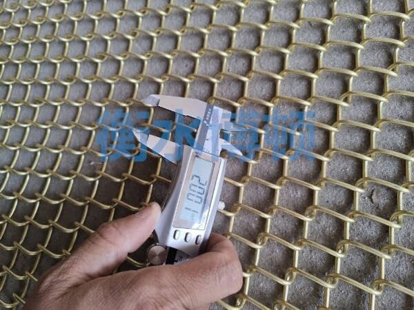 正在使用卡尺檢測銅合金網的網孔尺寸, 顯示為20mm.