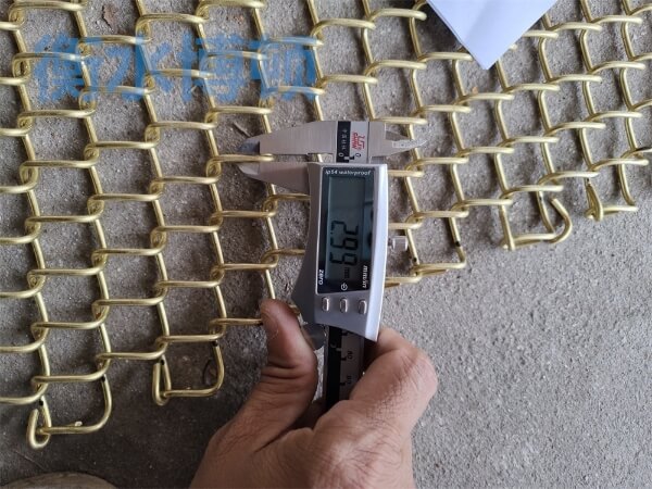 正在使用卡尺檢測銅合金網的網孔尺寸, 顯示為2.99mm.